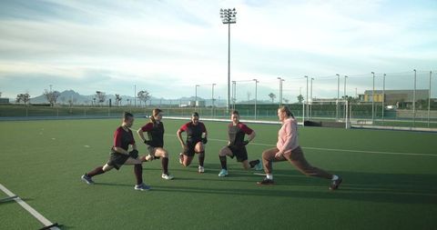 Female Athletes Practicing Stretches Outdoor Hockey Field