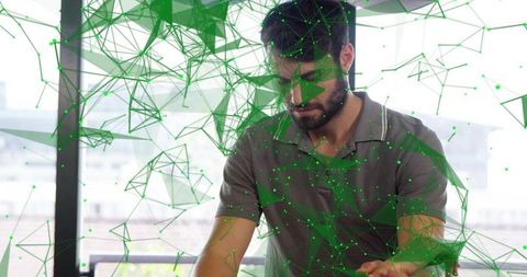 Bearded professional interacting with augmented green network visualization in workspace