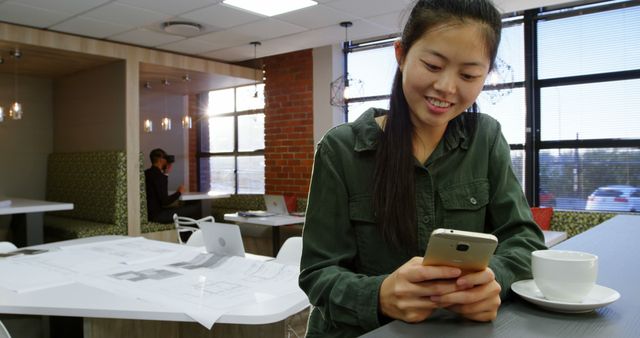 Young Woman Texting on Smartphone in Modern Cafe with Coffee and Blueprints - Download Free Stock Images Pikwizard.com