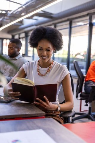 Young woman reading book in modern coworking space