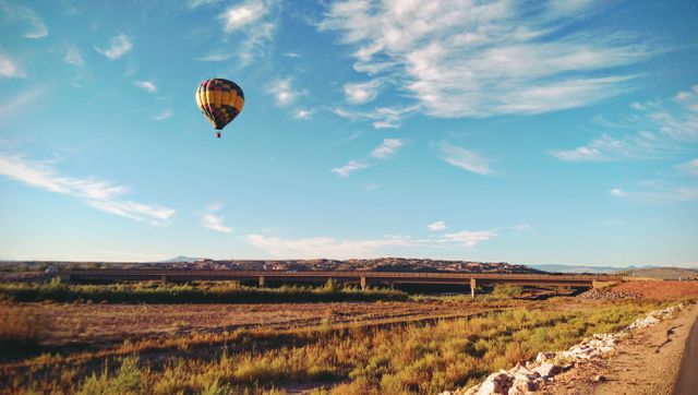 Hot air balloon flying over desert with blue sky and rocky terrain. Great for travel promotions, desert tourism, adventure themes, scenic views, and outdoor activities marketing.