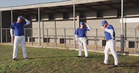 Three Male Baseball Players Adjusting Caps on Field During Warmup