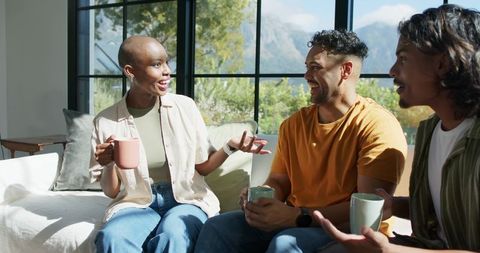 African american friends enjoying cozy coffee chat, sipping coffee and laughing in sunlit room