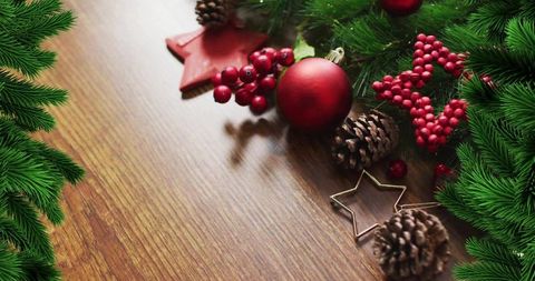 Rustic christmas table corner with red bauble, pine cones, berries and evergreen branches