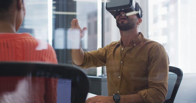 Man using a VR headset in an office, engaging in innovative and interactive technology. Can be used in articles or advertisements related to business innovation, high-tech offices, or virtual collaboration tools.
