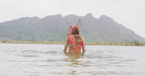 Woman wading in tranquil mountain lake