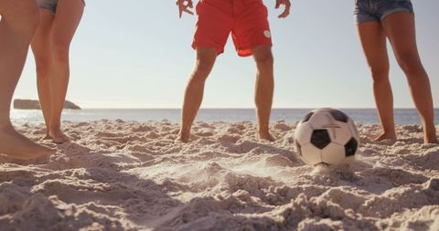 Young Adults Playing Soccer on Sandy Beach at Sunset
