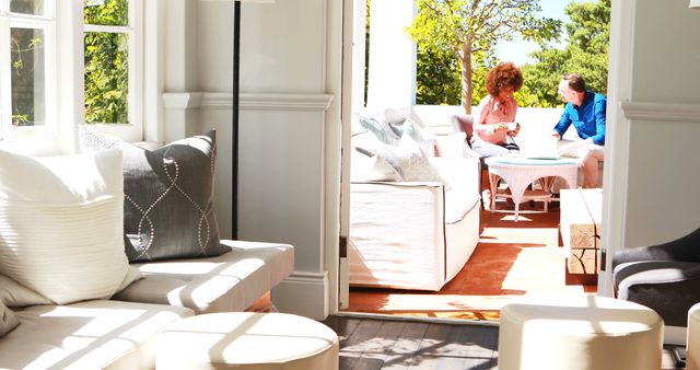 Couple enjoying coffee on sunlit patio seen from modern living room - Download Free Stock Images Pikwizard.com