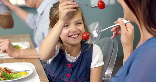 Mother and Daughter Sharing Cherry Tomatoes During Family Meal - Download Free Stock Images Pikwizard.com