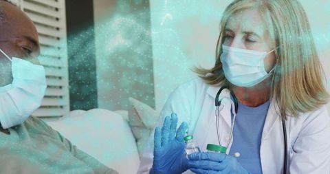 Clinician preparing vaccine vials during home visit with masked patient
