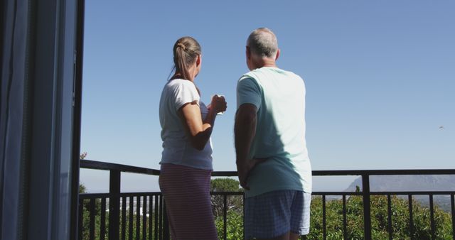 Caucasian senior couple standing on balcony talking in the sun. staying at home in isolation during quarantine lockdown.