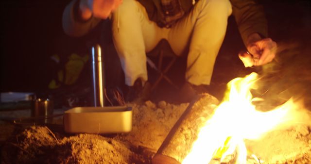 Person enjoying night camping around campfire with cooking equipment - Download Free Stock Images Pikwizard.com