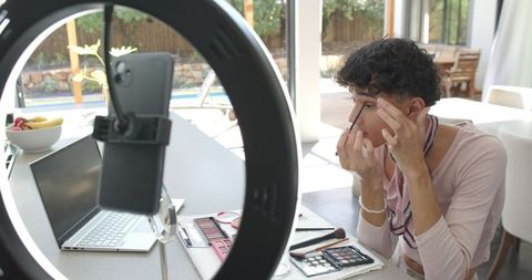 Person applying makeup using smartphone and ring light