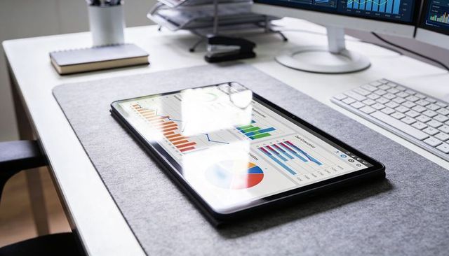 Tablet displaying colorful analytics dashboards on modern office desk with keyboard