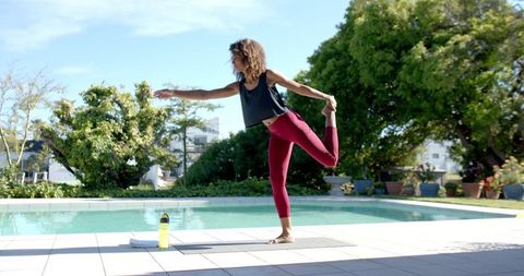 Woman Practicing Yoga by Poolside with Focus and Balance