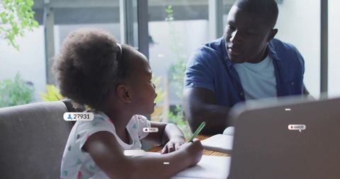 Father tutoring daughter with laptop and homework, focused learning and mentoring