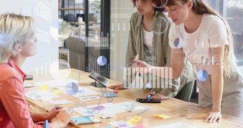 Women collaborating over prototypes and data dashboards on wooden table
