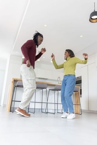 African american couple dancing in modern bright kitchen, casual home lifestyle