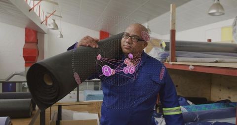 Textile worker carrying large fabric roll in industrial workshop with ar network overlay