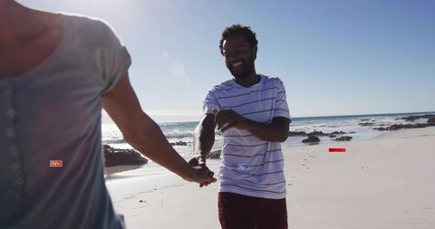Joyful couple walking hand-in-hand on sunny beach front