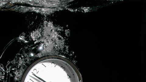 Alarm Clock Immersed in Water Against Dark Background