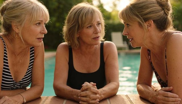 Three middle-aged women chatting poolside in swimsuits and jewelry, summer conversation