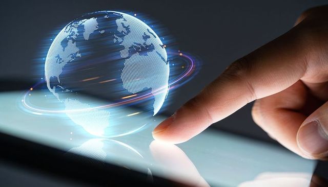 Touching tablet activating holographic globe with orbiting light trails and reflection