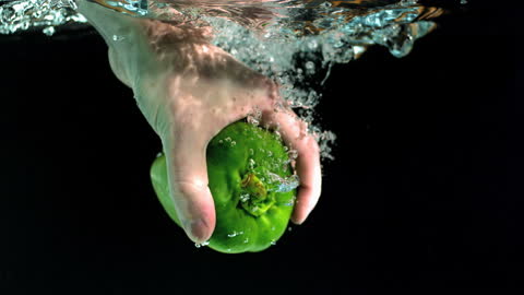 Hand Immersed Taking Fresh Green Pepper Underwater