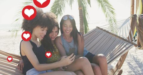 Female Friends on Beach Hammock Enjoying Social Media