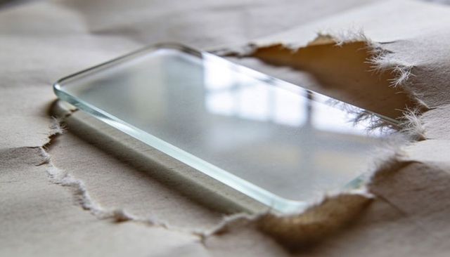 Clear rectangular glass pane on torn kraft paper reflecting window grid and paper fibers