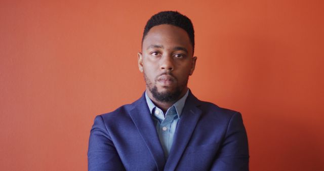 Image of serious african american man looking at camera on orange background. business professionals and working in office concept.