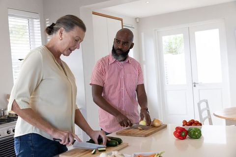 Diverse couple preparing vegetables together in modern kitchen