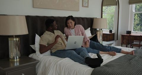 Relaxed couple shopping online with laptop and credit card on bed