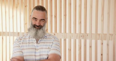 Bearded middle-aged man standing in front of wooden slat wall