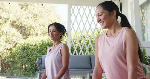 African american and indian women practicing yoga on sunlit porch for wellness lifestyle