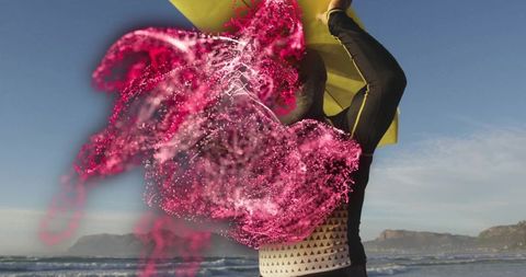 Athletic woman throwing magenta powder on beach