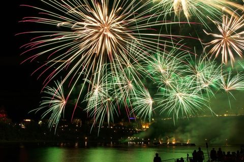 Vibrant Green Fireworks Illuminating Night Sky over River