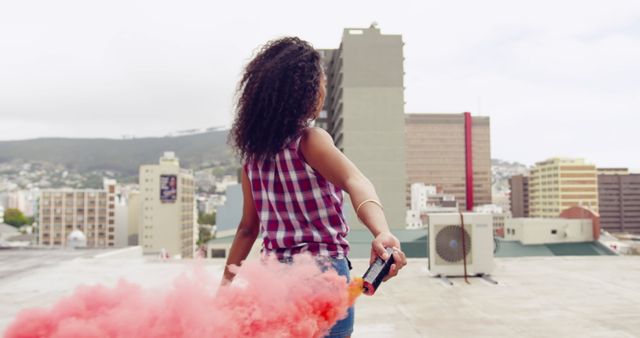 Woman Holding Smoke Bomb on Rooftop with Urban Buildings in Background - Download Free Stock Images Pikwizard.com