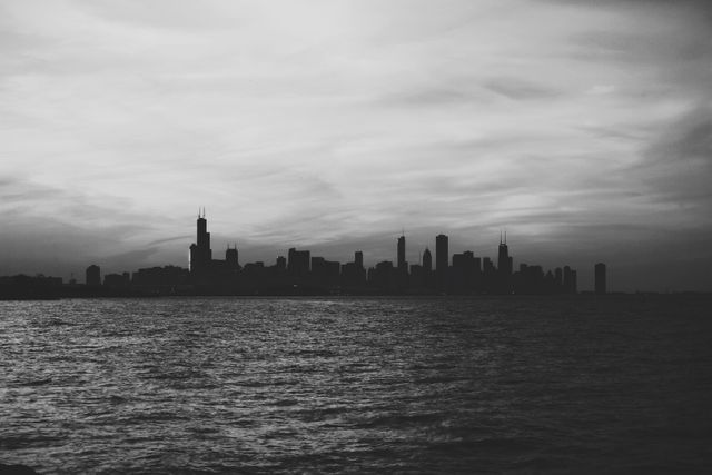 Chicago skyline with evening sunset casting dramatic shadows in black and white. The city buildings silhouette along the waterfront against a beautifully textured sky. Great for cityscape themes, urban lifestyle projects, travel guides, architectural studies, or art decor.