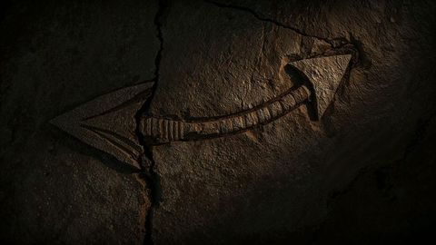 Ancient curved arrow carving on cracked stone with warm lighting