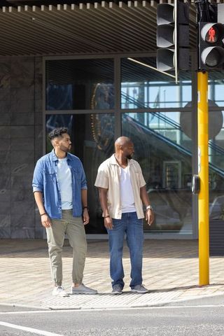 African american men waiting to cross at red pedestrian signal on urban sidewalk