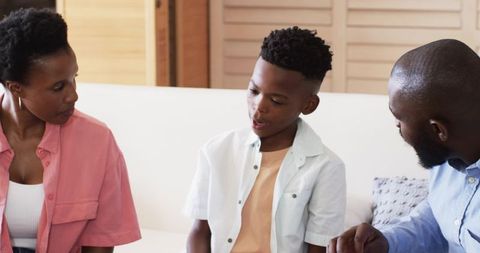 African American Parents Listening While Teen Son Sharing Feelings on Living Room Sofa