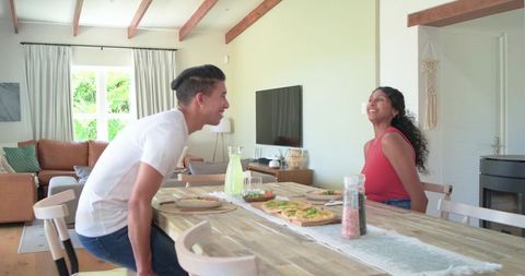African American couple laughing and chatting over casual lunch at sunlit dining table