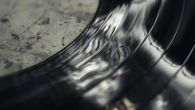 Macro glossy vinyl grooves capturing tactile scratches and dust on worn label