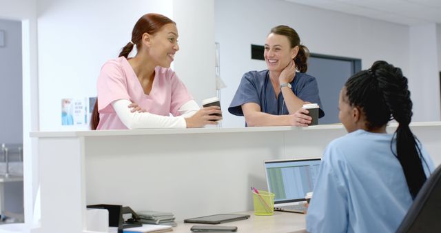 Healthcare professionals engaged in a discussion at a nursing station, fostering teamwork and collaboration. They wear scrubs indicating their different roles within the healthcare setting. Perfect for illustrating medical environments, teamwork in healthcare, hospital workplace dynamics, and professional interactions among medical staff.