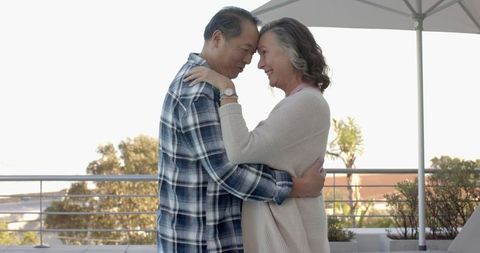 Mature Couple Embracing on Sunlit Rooftop Terrace