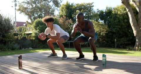 Diverse men exercising squats on outdoor deck for fitness lifestyle