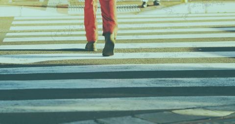Pedestrian crossing urban street in vibrant red pants