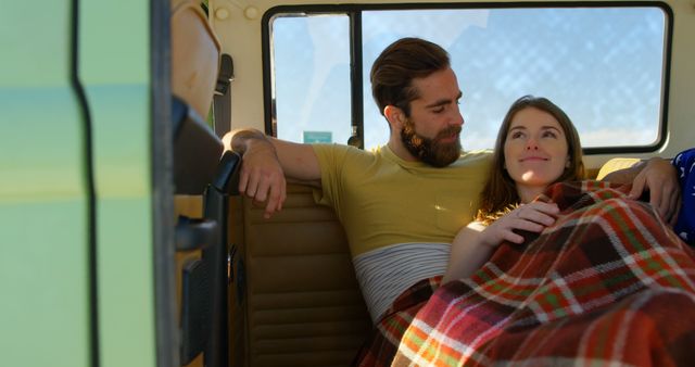 Couple enjoying a peaceful moment in the back of a camper van. Perfect for themes related to travel, adventure, young love, and leisure. Useful for promoting road trip destinations, travel blogs, camping gear, or cozy, romantic settings.