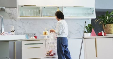 Senior Woman Cleaning Kitchen After Birthday Celebration